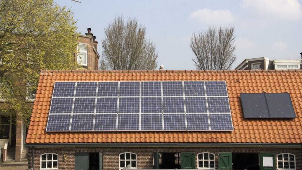 A house with a terracotta-tiled roof and solar panels, showcasing solar energy's versatility in overcast conditions. Demonstrates solar panels' ability to function effectively without direct sunlight.