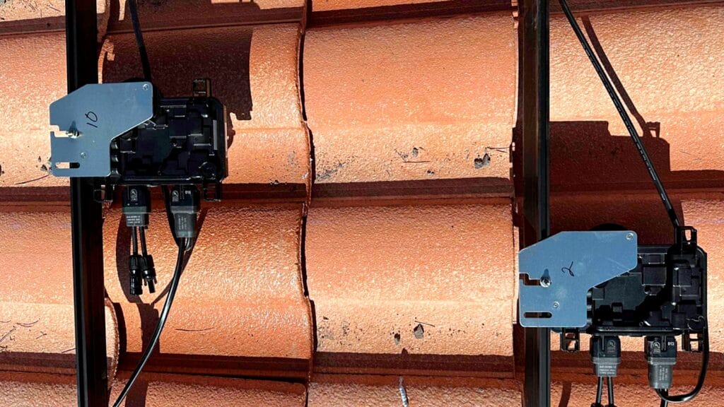 Microinverters and mounting rails on a shingled roof, prepared for solar panel installation.
