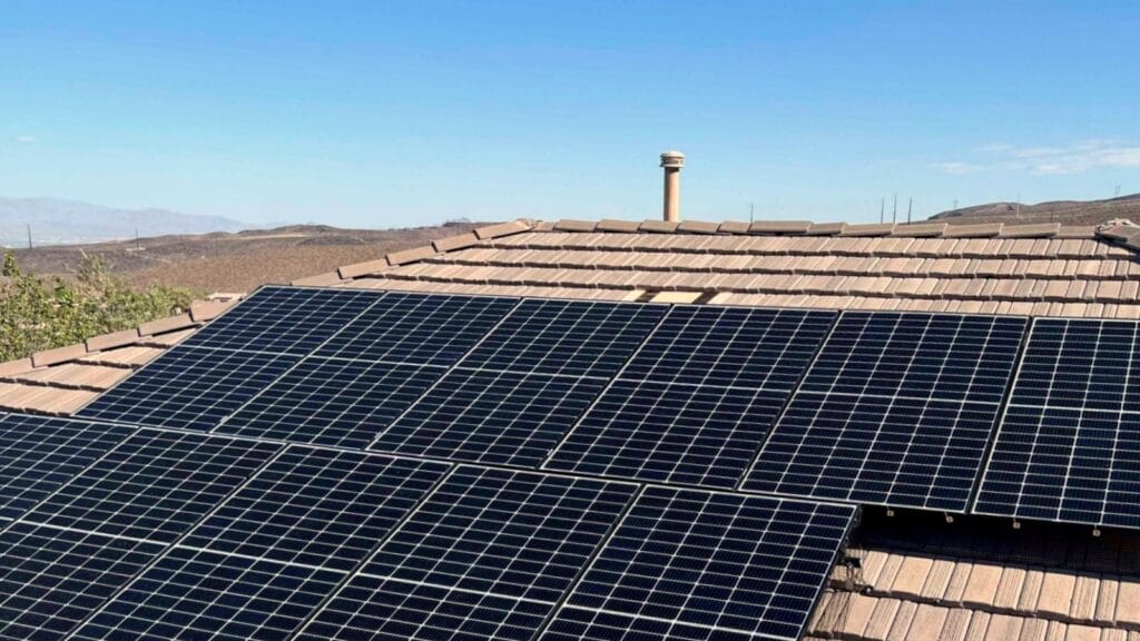 Solar panels installed on a residential roof under clear blue skies.