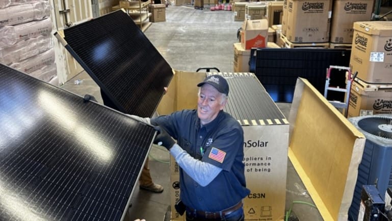 A professional handling solar panels in a warehouse, preparing them for installation