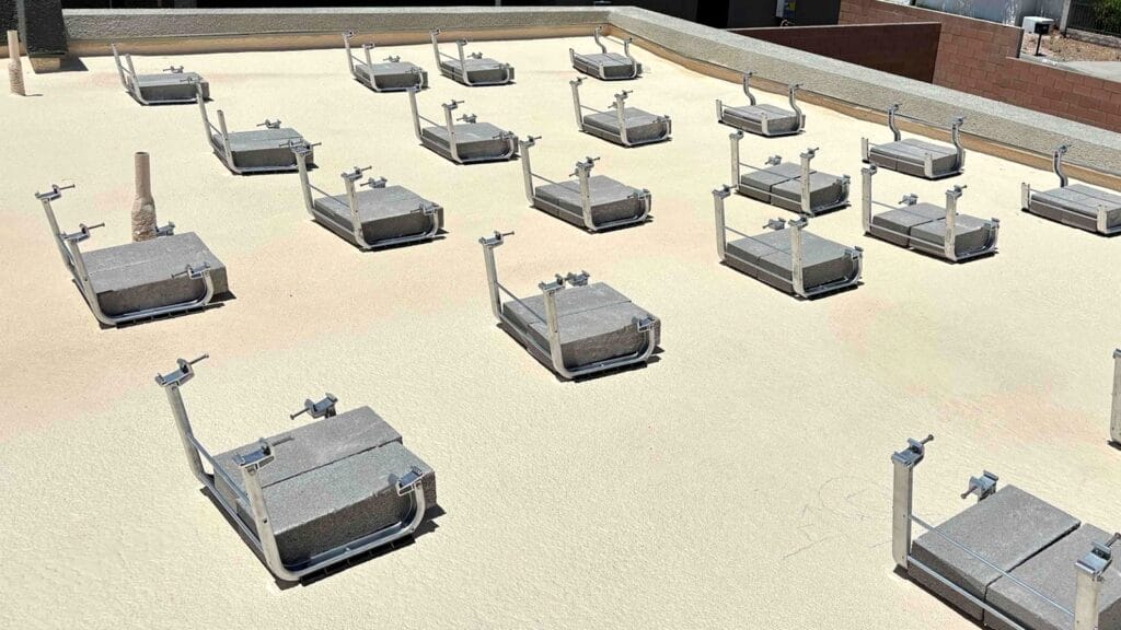 Flat roof prepared for solar panel installation with mounting brackets and concrete weights.