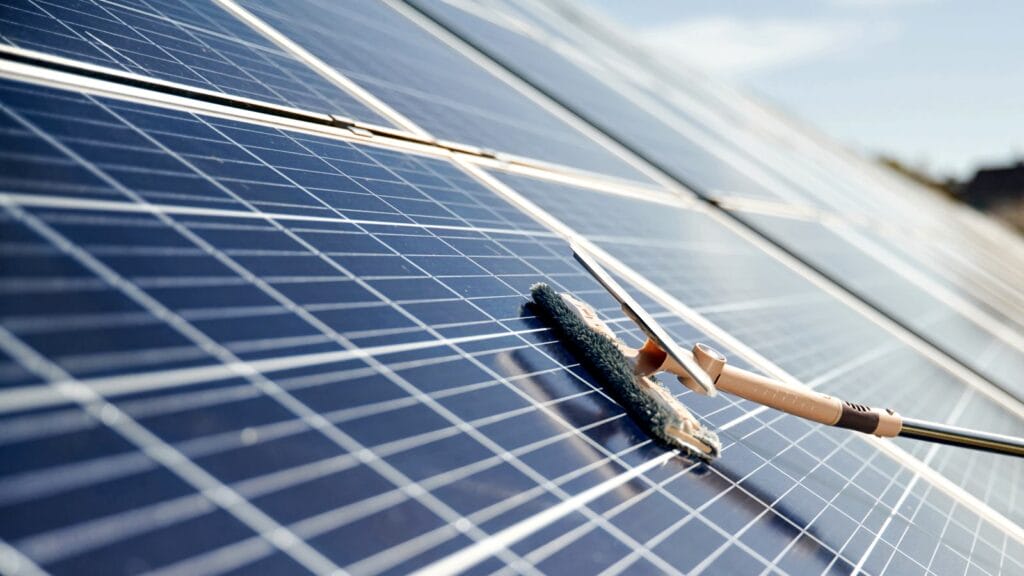 Cleaning solar panels gently using a soft brush and handle