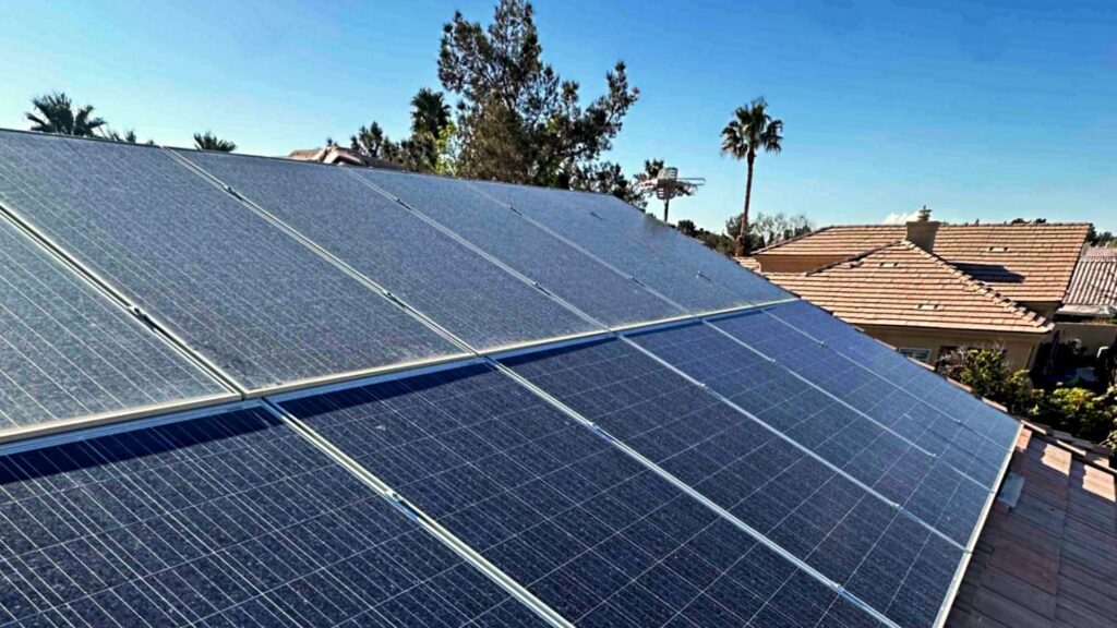 Residential rooftop solar panels installed on a red tile roof in a Las Vegas neighborhood under clear blue skies.