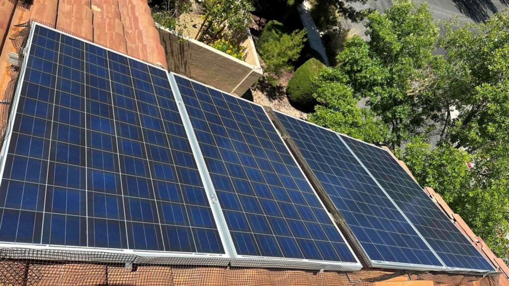 Tile-roof solar array on a Las Vegas home with three blue photovoltaic panels mounted at tilt beside an HVAC unit.