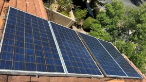 Tile-roof solar array on a Las Vegas home with three blue photovoltaic panels mounted at tilt beside an HVAC unit.