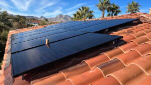 Solar panels installed on a red tile roof of a Las Vegas home with desert mountains and palm trees in the background